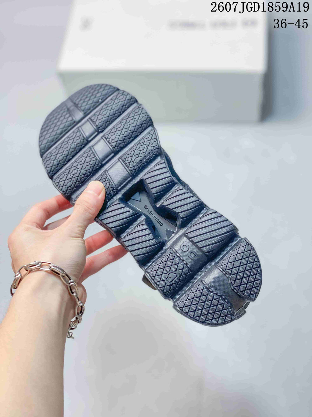 Underside view of a dark sneaker showing the segmented outsole, textured tread, and On branding.