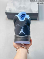 Rear view of a dark high-top sneaker with a Jumpman-style heel emblem and light blue collar lining.