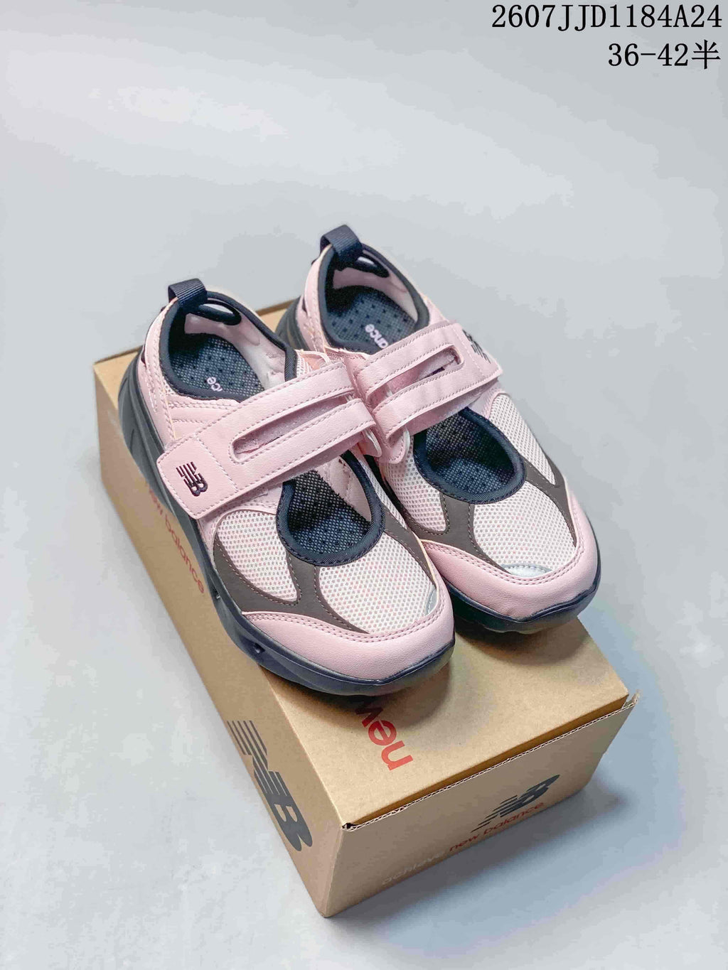 Pair of pink, gray, and dark navy New Balance Mary Jane sneakers displayed on a New Balance shoe box; image text shows sizes 36–42.