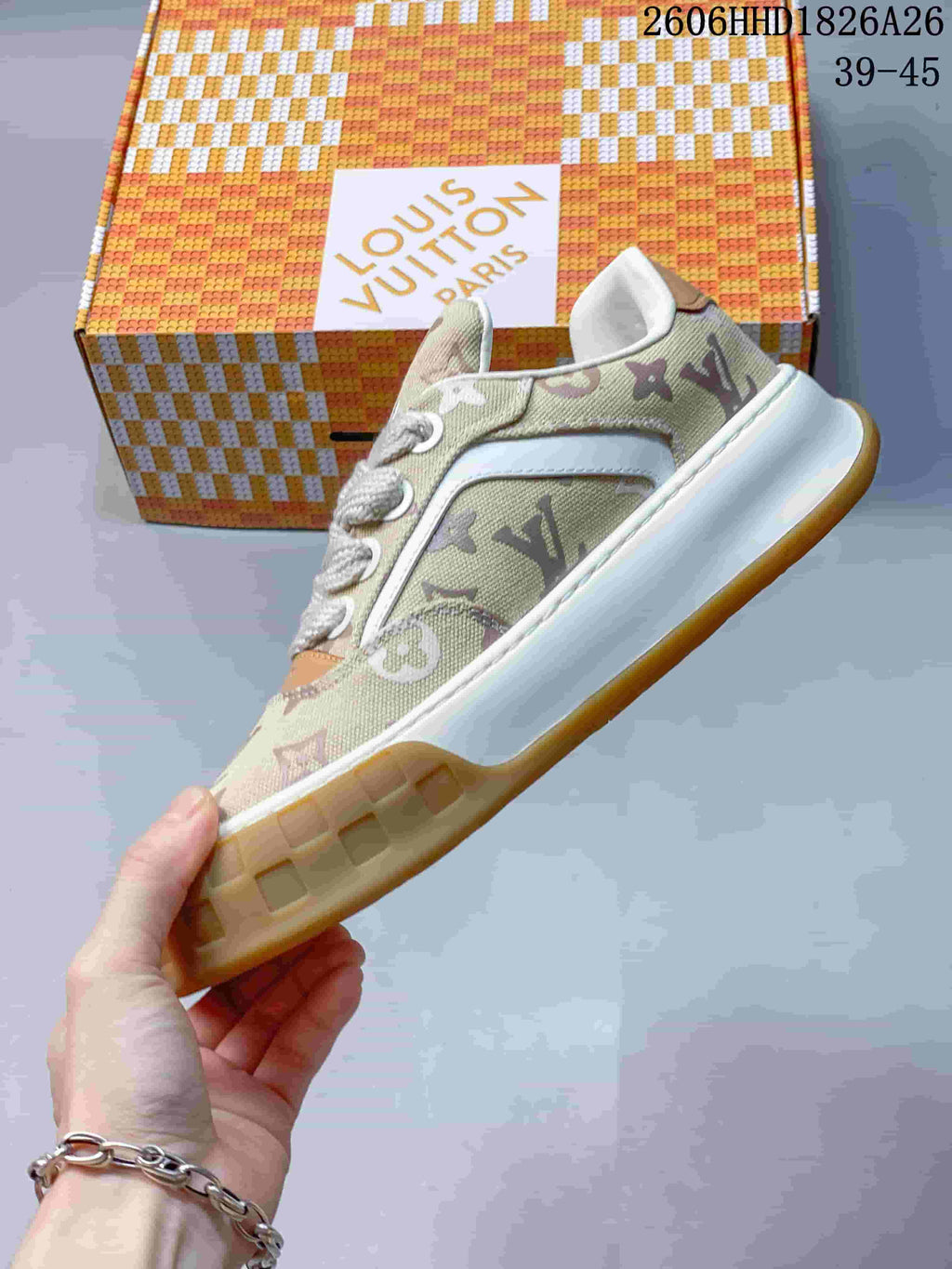 Side profile of a beige monogram-patterned low-top sneaker with white trim and a gum-colored outsole.