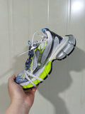 Close-up side view of silver and white low-top sneakers with neon green, blue and black accents.