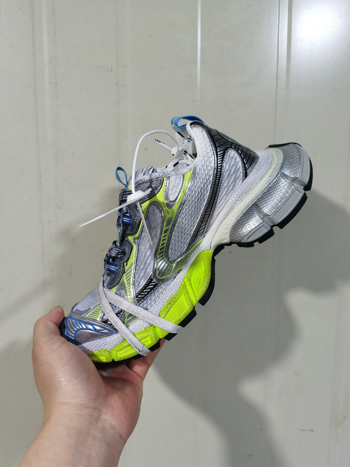 Close-up side view of silver and white low-top sneakers with neon green, blue and black accents.