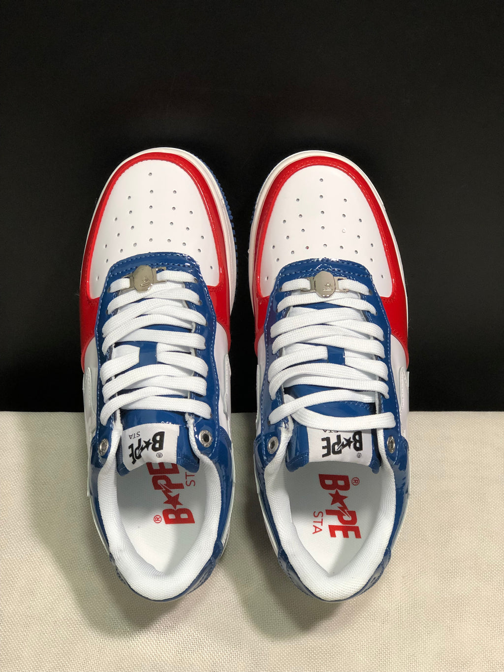 Top view showing white perforated toe boxes, blue eyestays, white laces, and branded insoles.