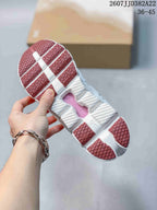 Underside view of the sneaker showing the segmented white outsole, pink traction sections, and central cutout detail; style code and size range are visible above.