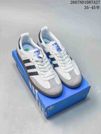 Pair of white adidas Originals Samba sneakers with black stripes, gray toe panels and a blue adidas shoebox; source text shows style code 2607ND1087A27 and size range 35–45.5.