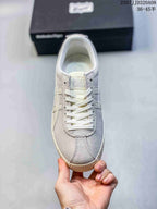 Front view of a light gray and off-white lace-up ASICS sneaker showing the padded collar, tongue branding, and rounded toe.