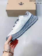 Side profile of the white low-top sneaker with gray midsole and navy detailing