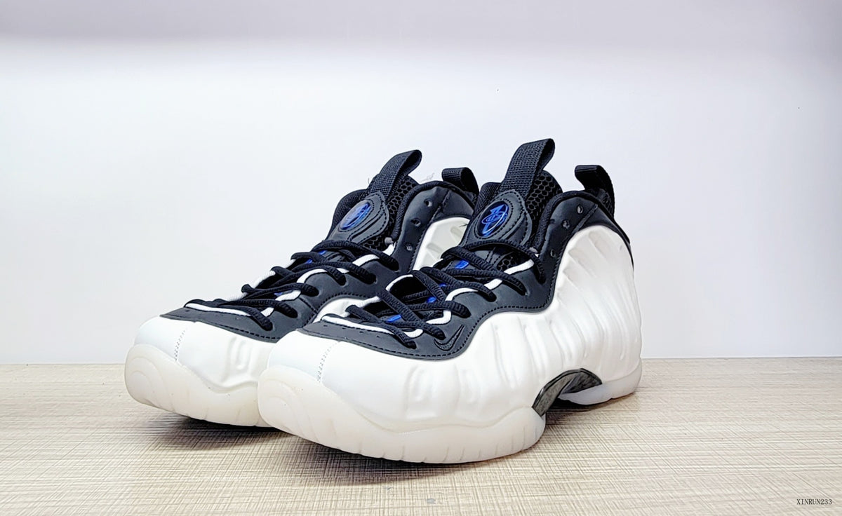 Pair of white, black and blue Nike Air Foamposite One high-top sneakers, front three-quarter view