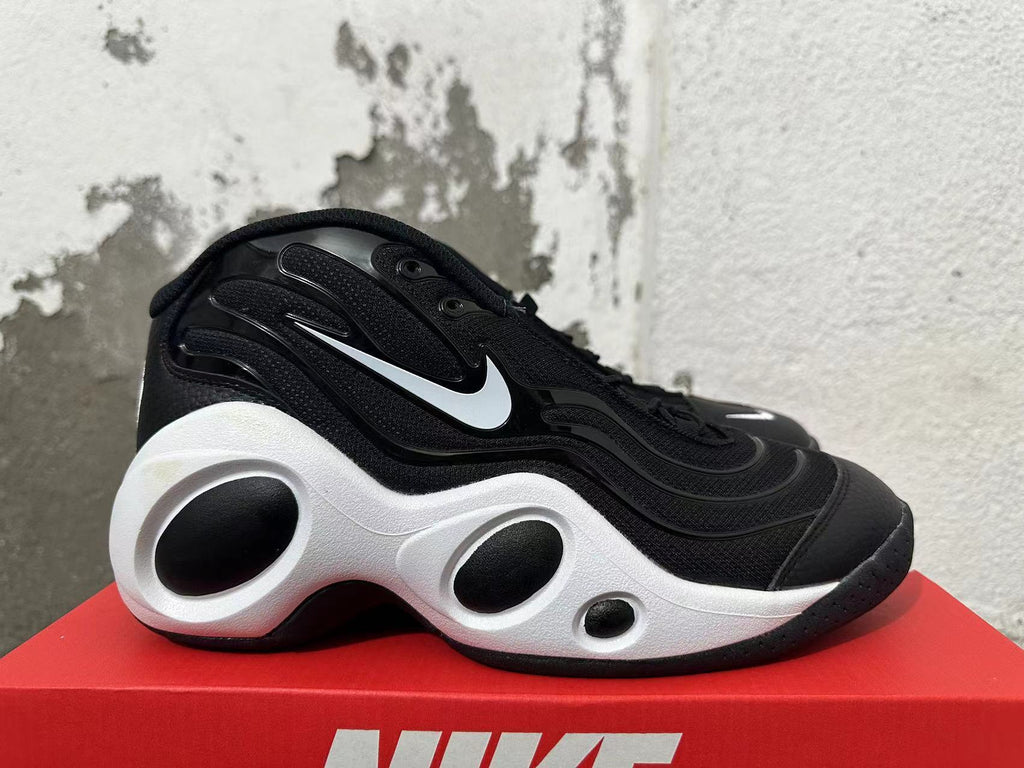 Side view of a black sneaker with a white Swoosh and sculpted white midsole.