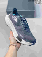 Angled side view of the dark gray sneaker showing the The North Face logo, mesh upper, white midsole, and lugged outsole.