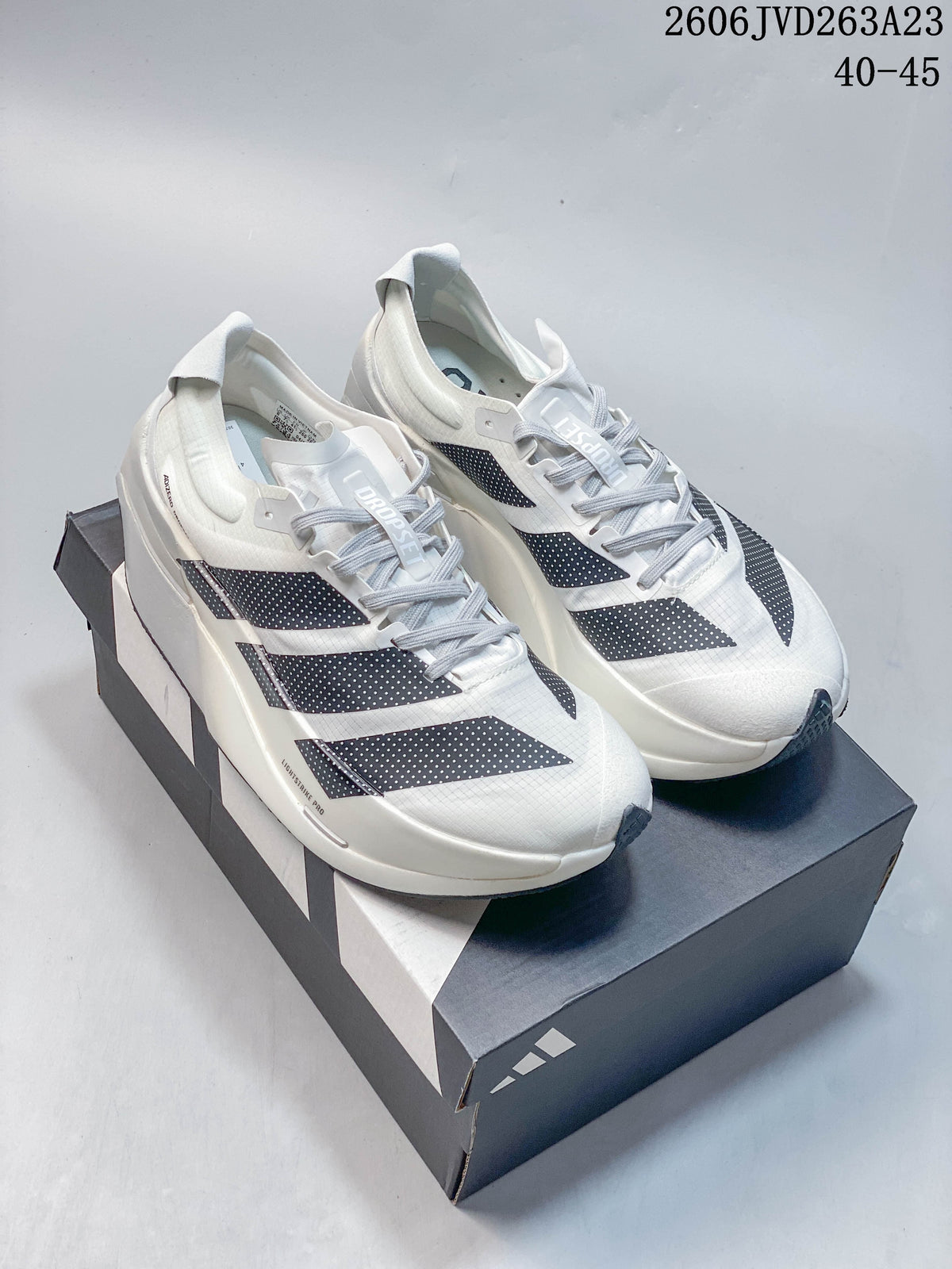 White Adidas Adizero Dropset Elite shoes with dark side stripes displayed on a shoebox; image text shows sizes 40–45.