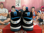 Rear view of black basketball shoes with blue heel accents, white heel panels, and blue pull tabs.