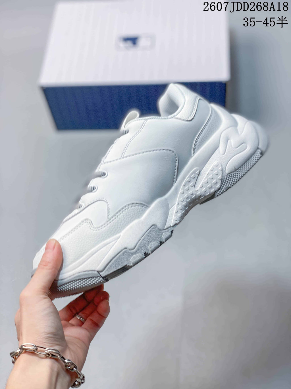 Side profile of the white low-top sneaker showing layered panels, a raised heel section and textured outsole.