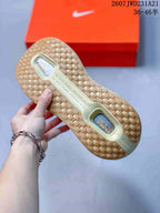 Underside view showing the sneakers' gum-colored patterned outsole and visible cushioning windows.