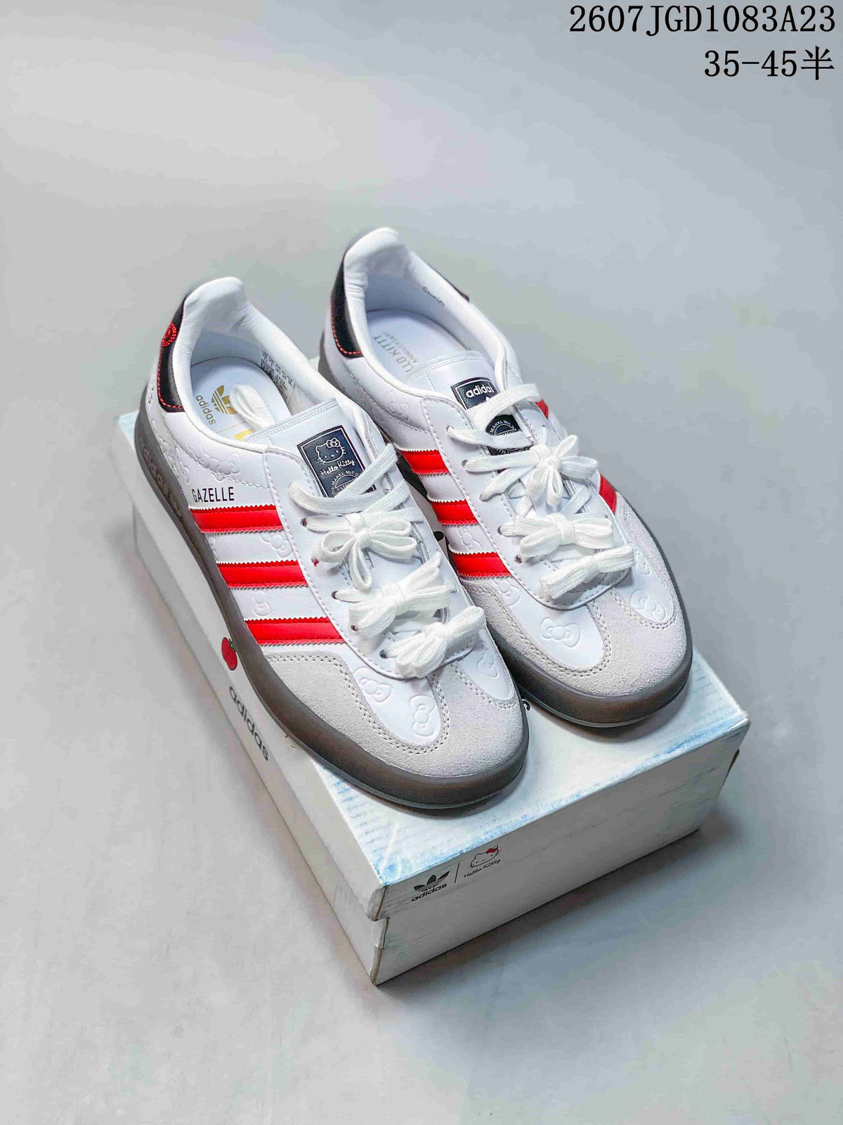 Pair of white and red adidas Gazelle sneakers with Hello Kitty detailing displayed on a shoebox; image text shows product code 2607 JGD1083A23 and sizes 35–45.