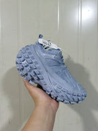 Moon-gray chunky sneaker shown from a three-quarter side angle, highlighting the layered mesh upper and lugged outsole.