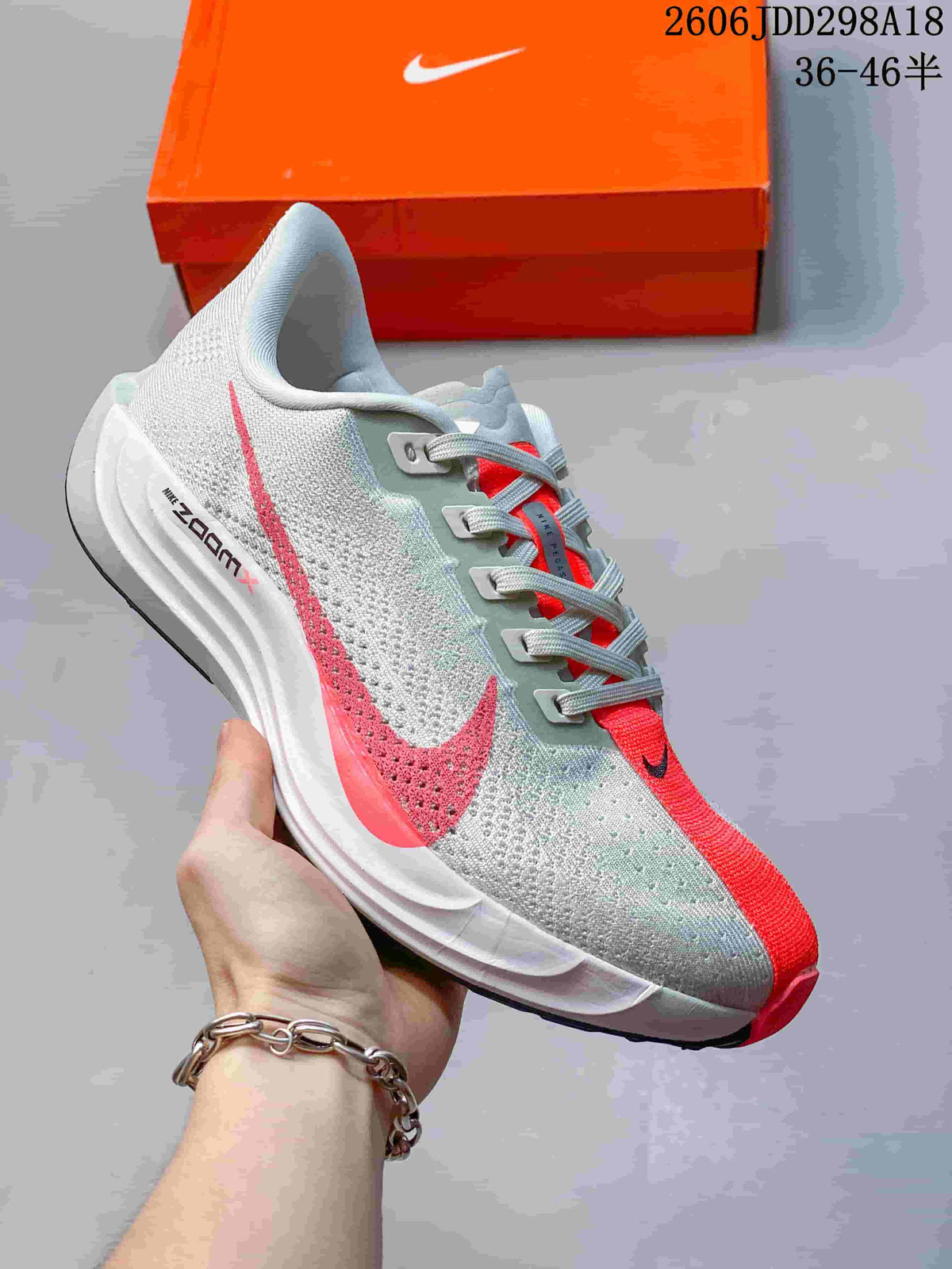 Angled side view showing the textured grey upper, red Swoosh, red toe accent, white midsole, and visible ZoomX branding.