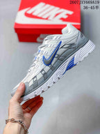 Side view of the sneaker showing the layered white and grey upper, blue Swoosh, and textured outsole.