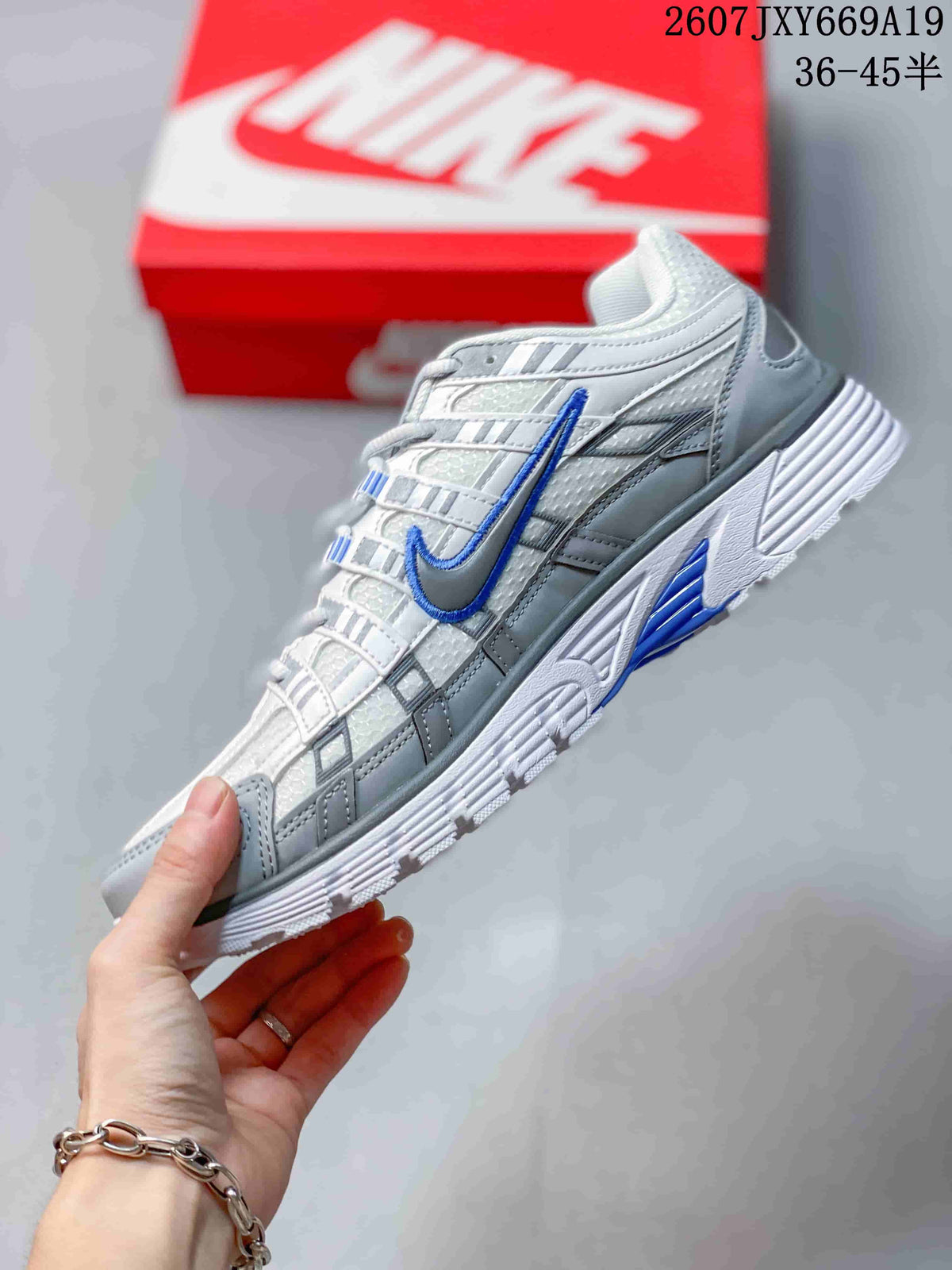 Side view of the sneaker showing the layered white and grey upper, blue Swoosh, and textured outsole.