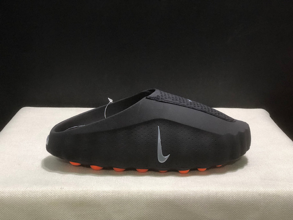 Single black slide in side profile with a textured upper, side Nike branding, and orange outsole pods.