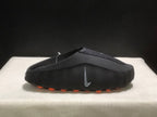 Single black slide in side profile with a textured upper, side Nike branding, and orange outsole pods.
