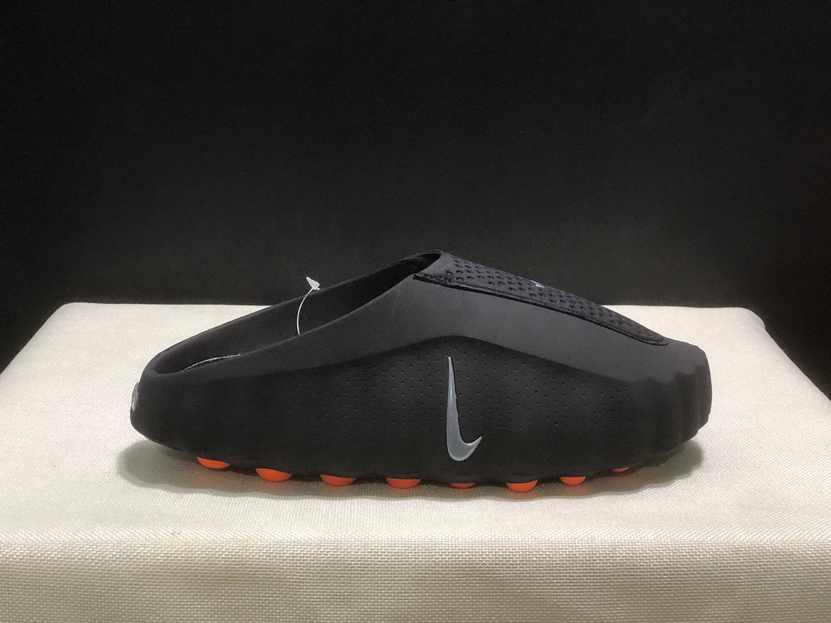 Single black slide in side profile with a textured upper, side Nike branding, and orange outsole pods.