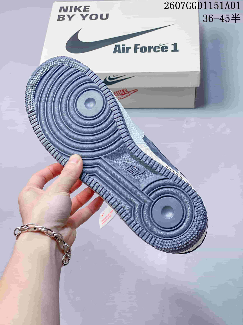 Blue-gray outsole of a sneaker shown beside an Air Force 1 style shoe box