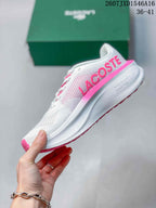 Side view showing the white textured upper, pink Lacoste branding, and sculpted sole.