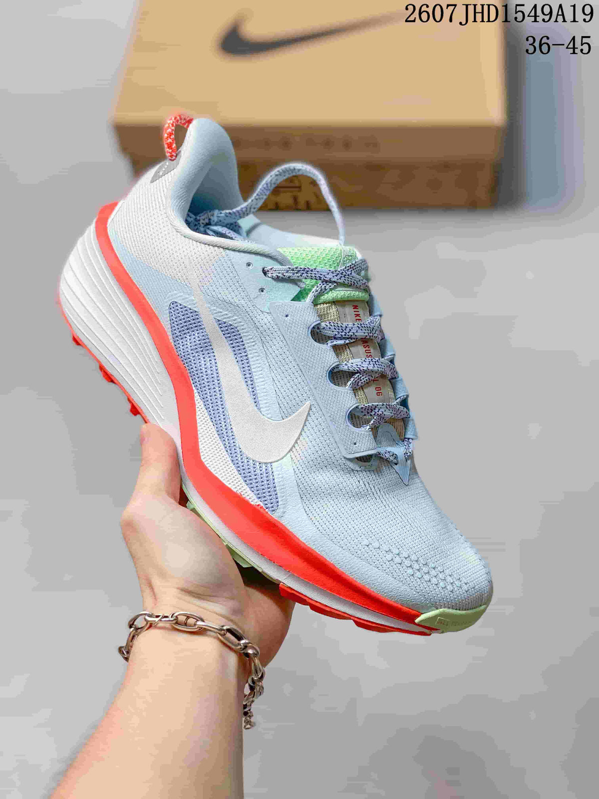 Light gray Nike Zoom Fly 5 sneaker with a white Swoosh, pale blue details, and bright coral sole accents.