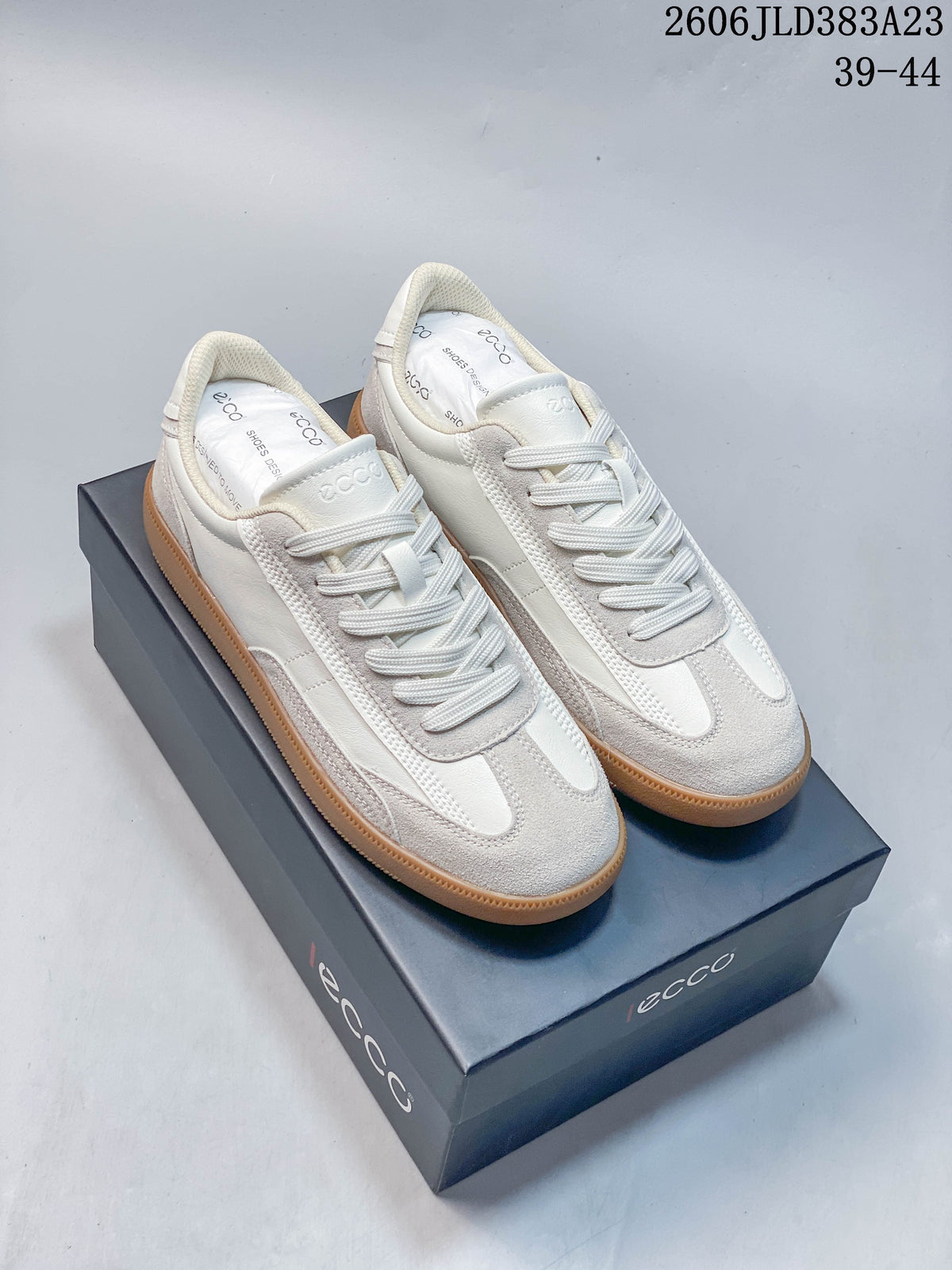 Pair of off-white ECCO low-top sneakers with textured overlays and gum-colored soles, displayed on a branded box; image overlay shows sizes 39–44 and code 2606 JLD383A23.
