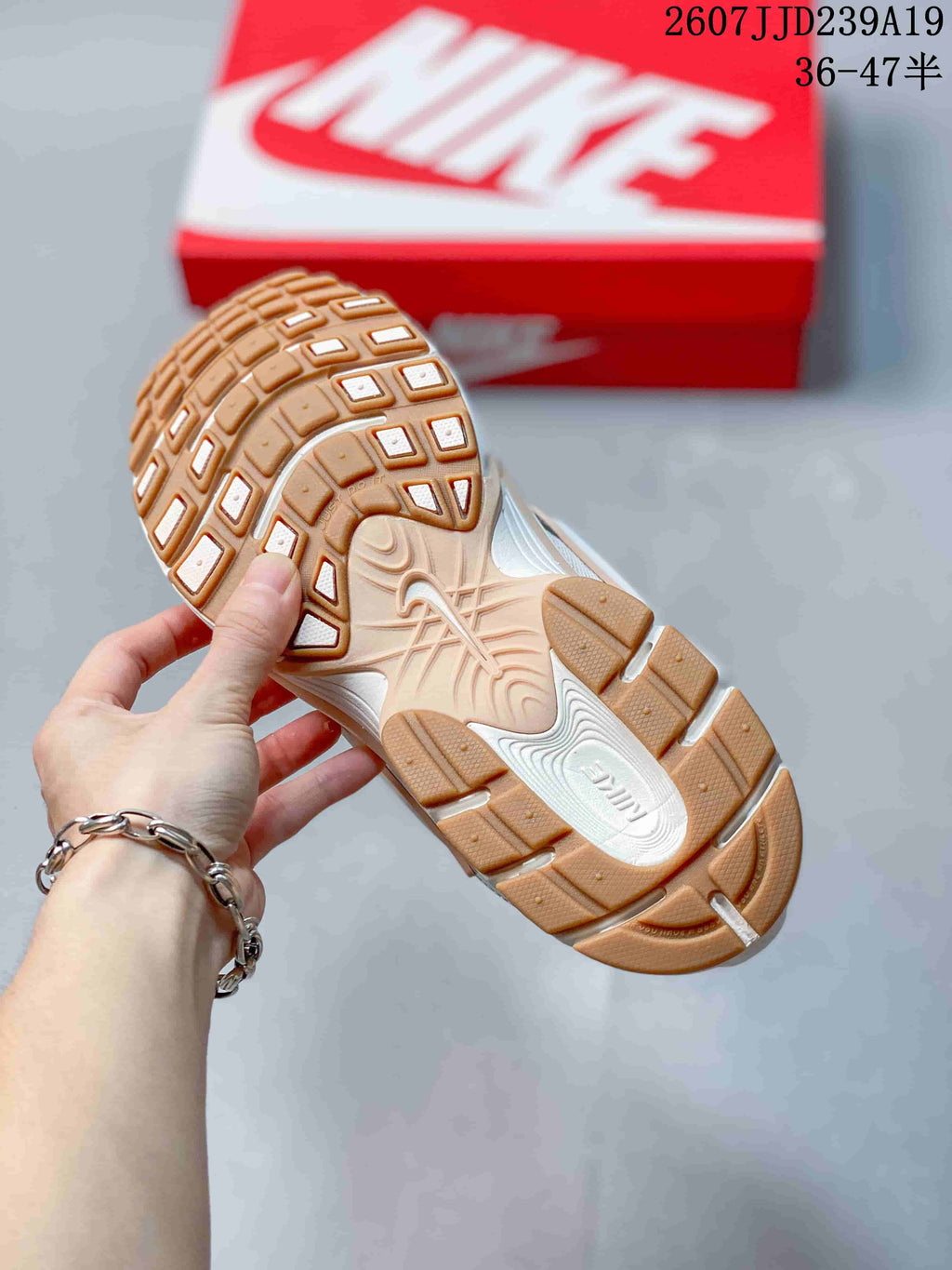 Close view of the gum-toned outsole with segmented traction blocks and a red Nike shoebox in the background.