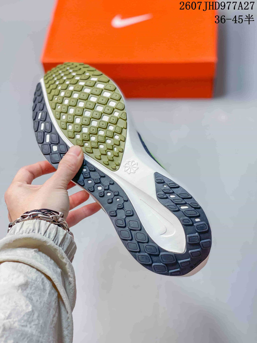 Underside view of the sneakers showing the contrasting patterned outsole in dark navy and olive lime sections.