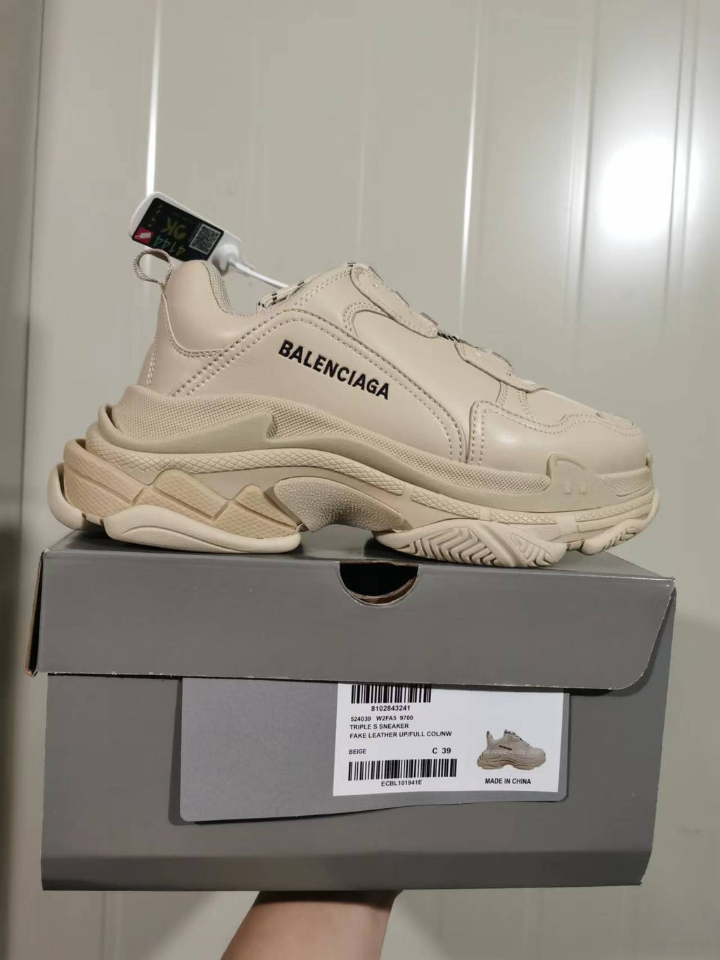 Beige Balenciaga Triple S sneaker displayed on its box, showing the side branding, chunky layered sole, and box label.