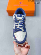 Top-down view of the sneaker showing white perforated toe material, navy overlays, and alternating navy and white laces.