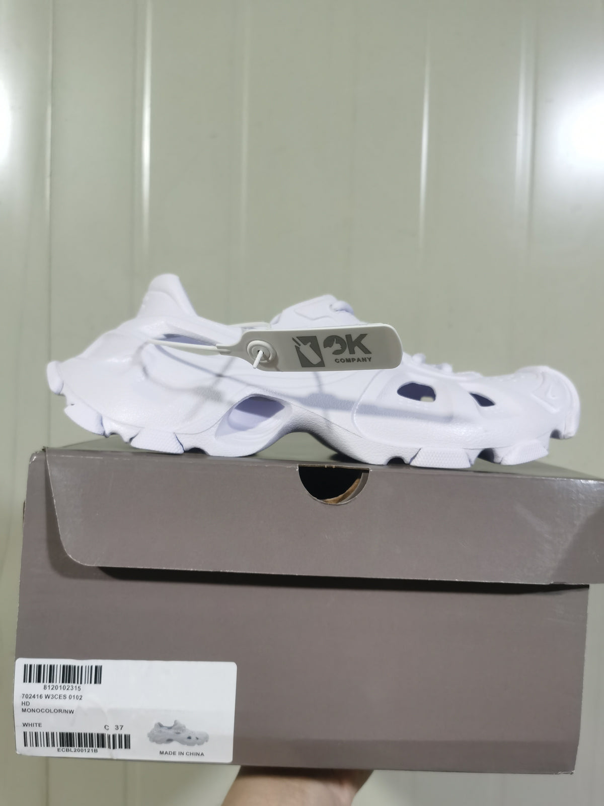 Side view of the white open-panel sneaker resting on a shoe box; the box label shows a photographed size of C 37 and the color WHITE.