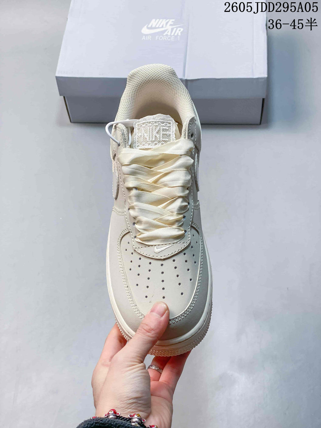 Top view of a cream sneaker showing the perforated toe box, woven tongue label, and wide laces.