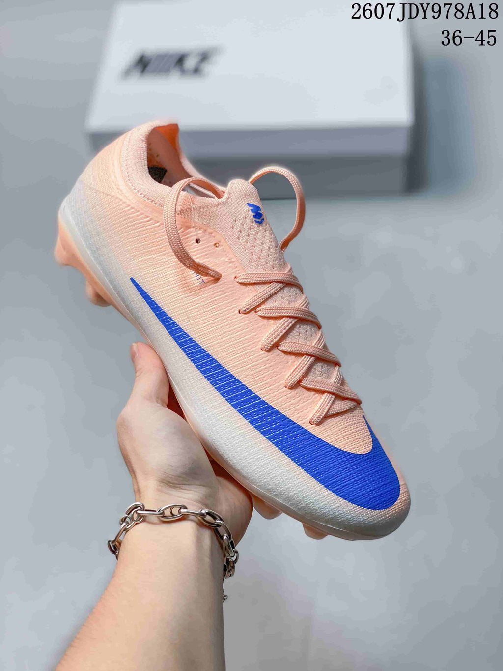 Light pink and white Nike soccer cleat with a blue side detail and translucent molded studs.