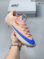 Light pink and white Nike soccer cleat with a blue side detail and translucent molded studs.