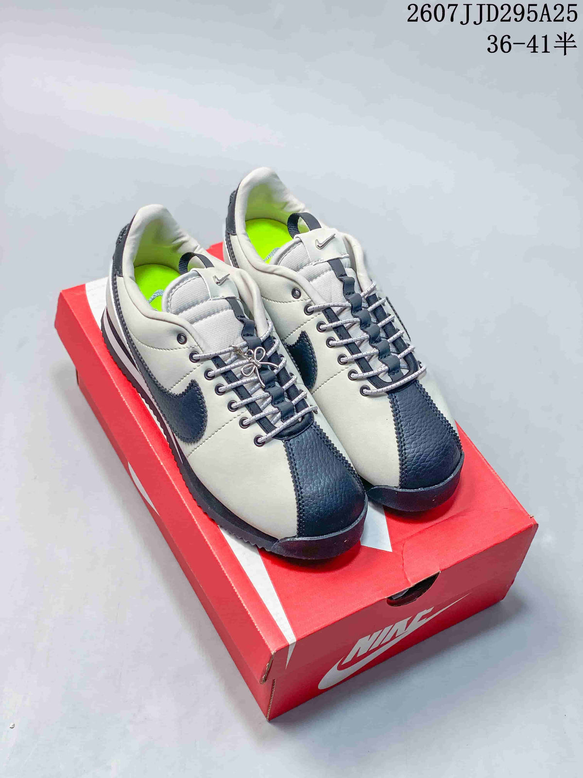 Pair of white and dark navy Nike Classic Cortez sneakers displayed on a red Nike shoebox.