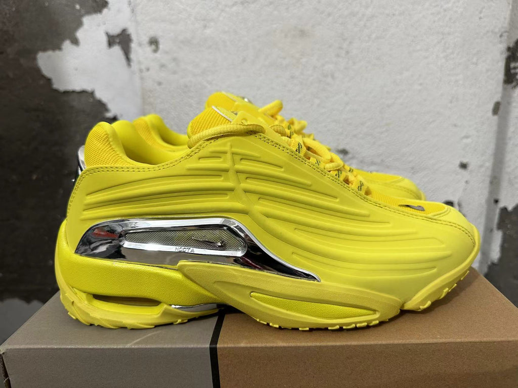 Side view of yellow sneakers with sculpted detailing and a silver-tone NOCTA accent.