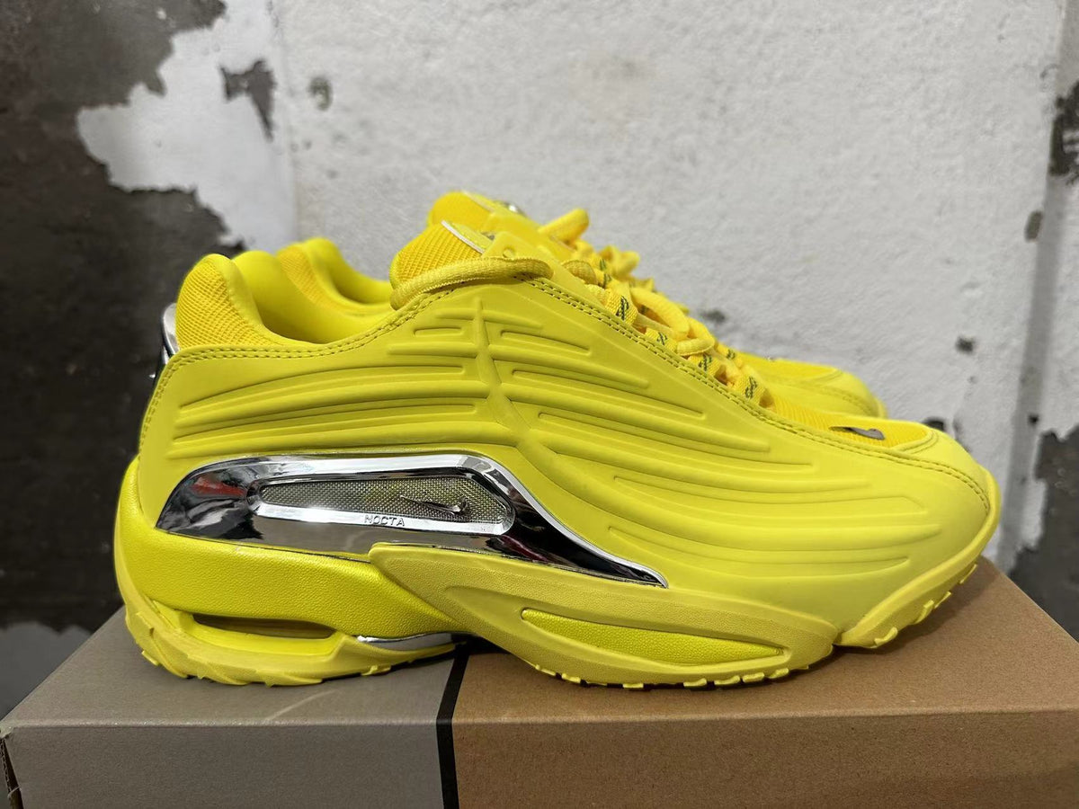 Side view of yellow sneakers with sculpted detailing and a silver-tone NOCTA accent.