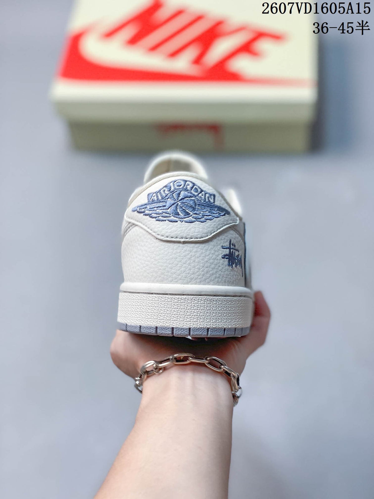 Rear view showing the textured white heel, blue embroidered winged basketball emblem, and gray outsole edge.