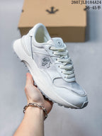 Angled side view of the white Descente sneaker showing the layered upper, lace-up closure and treaded sole.