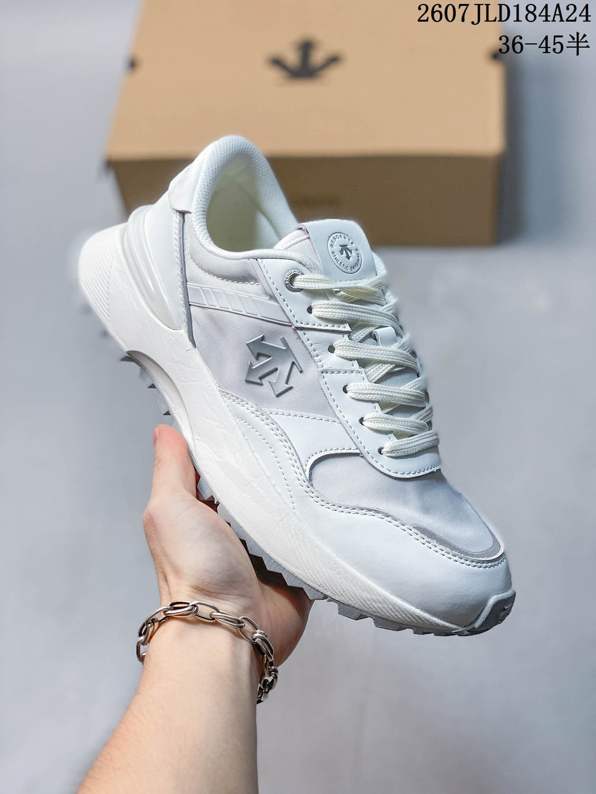 Angled side view of the white Descente sneaker showing the layered upper, lace-up closure and treaded sole.