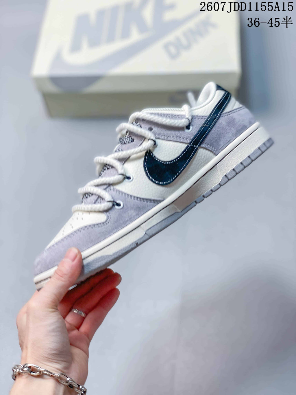 Side profile highlighting the dark navy Swoosh, gray overlays, white upper panels, layered midsole, and gray outsole.