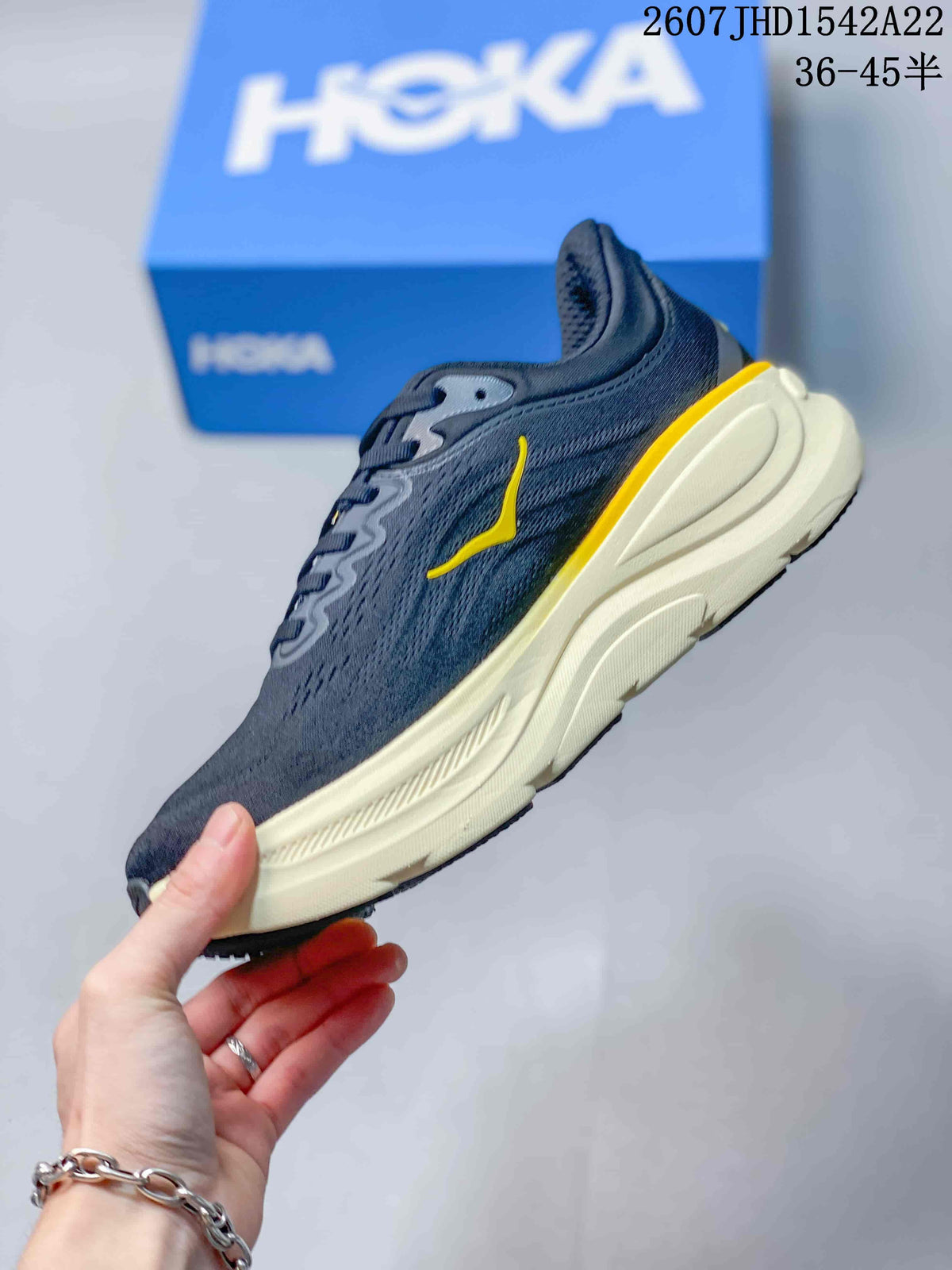 Side profile of the charcoal-black sneaker showing the yellow side logo, lace-up upper and sculpted cream midsole.