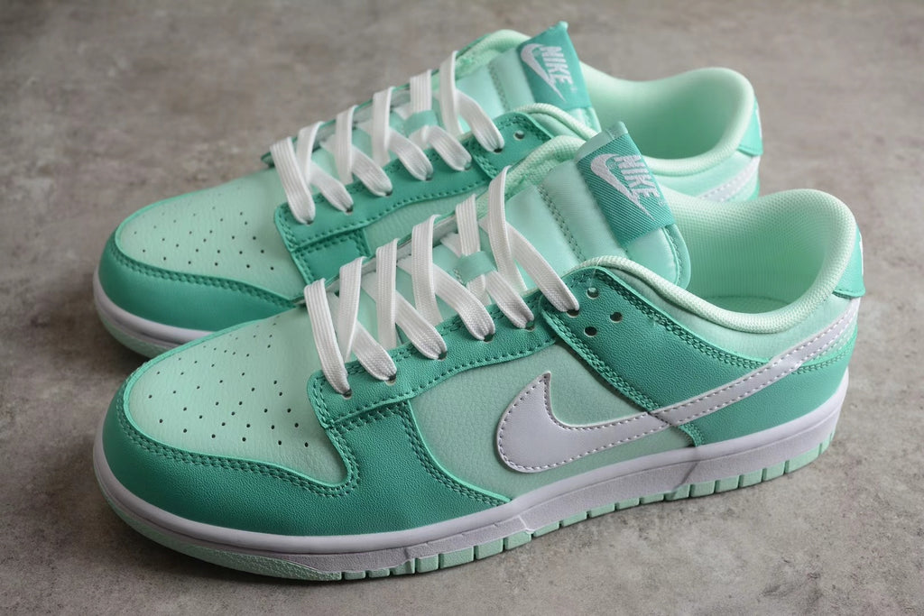 Three-quarter view of the pair showing the mint green and white low-top design with contrasting Swoosh logos.