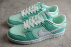Three-quarter view of the pair showing the mint green and white low-top design with contrasting Swoosh logos.