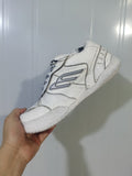 Side view of a white Balenciaga sneaker showing the outlined side logo, layered upper panels, laces, and textured sole.