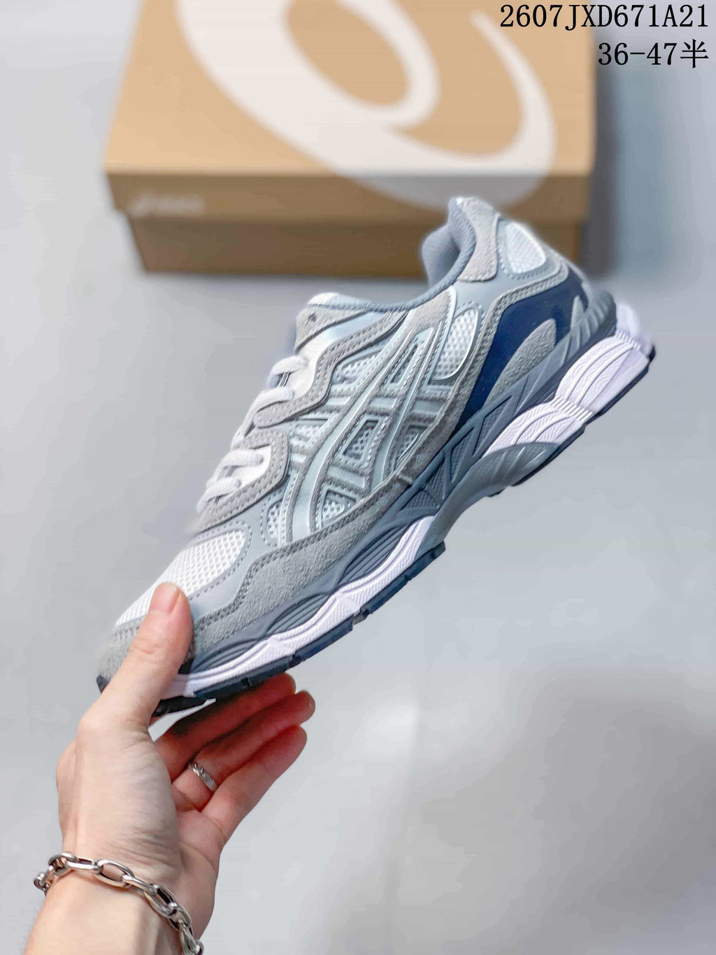 Side profile of a gray and white ASICS GEL-Kayano 14 sneaker showing layered panels, mesh sections and a segmented sole.